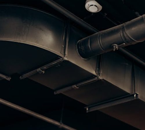 Detailed view of industrial air ducts on a ceiling, showcasing modern urban design.